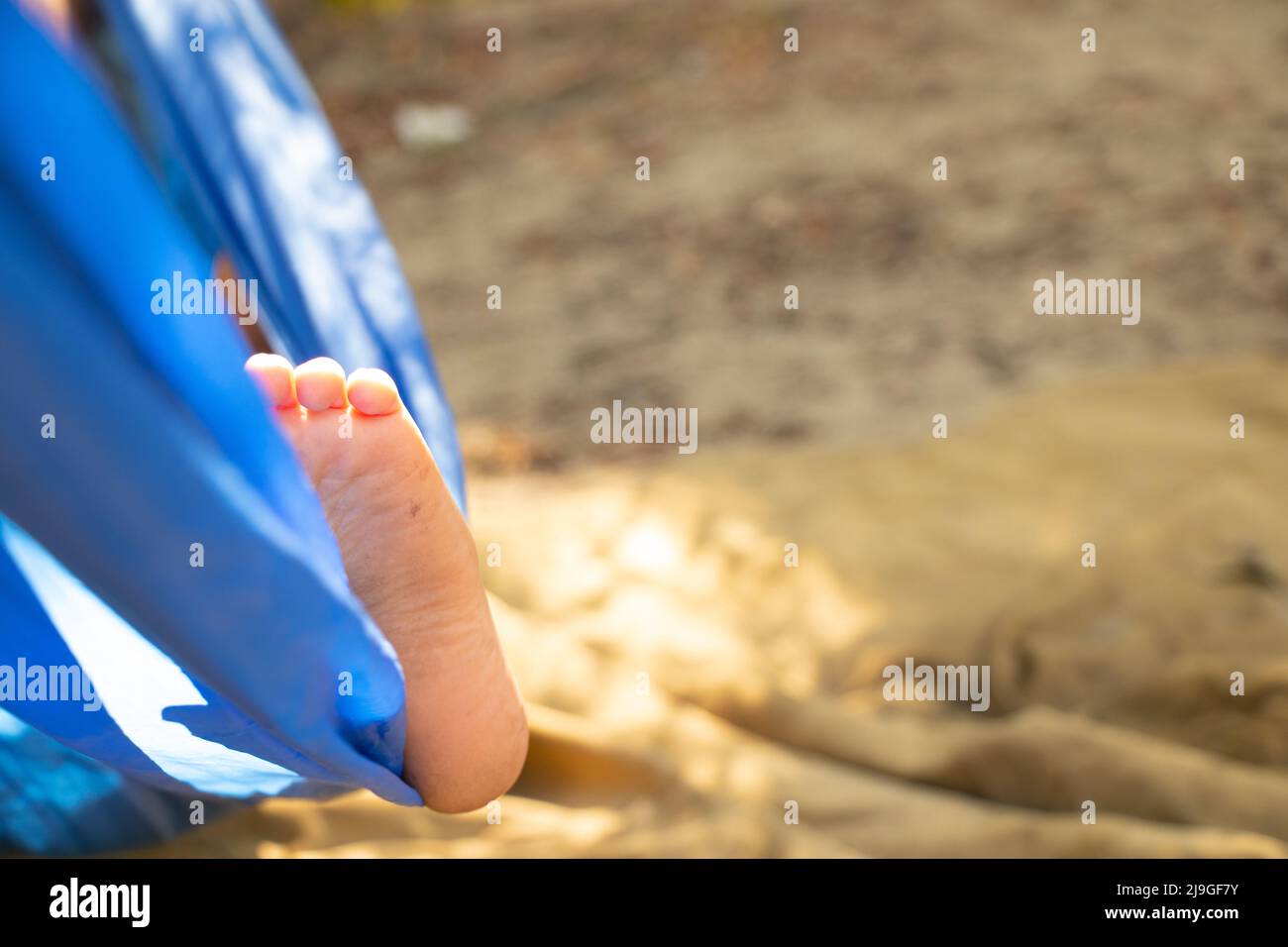 le pied des enfants dans un hamac, roulant dans la forêt en été au soleil, se reposer dans un hamac, un pied dans un hamac, se reposer dans la forêt Banque D'Images