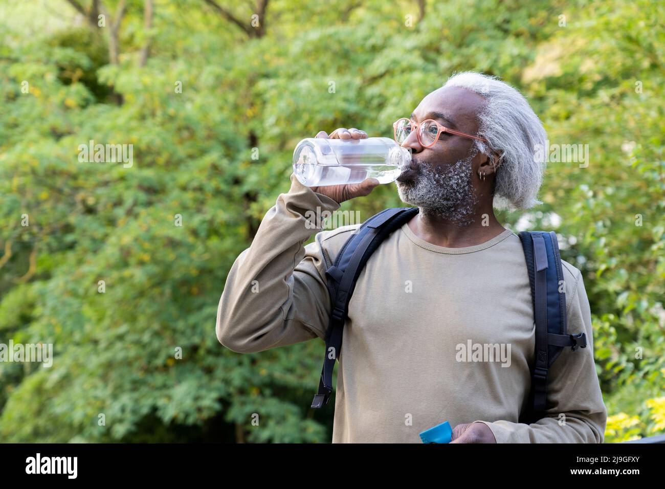 Homme senior qui boit de l'eau et qui regarde loin Banque D'Images