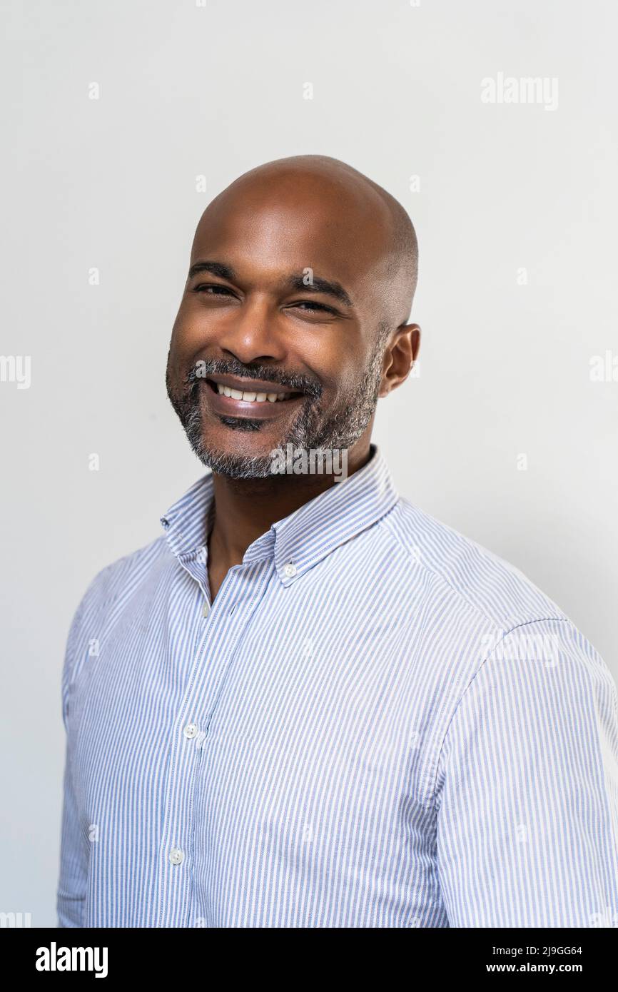Gros plan d'un homme souriant debout contre un mur blanc Banque D'Images