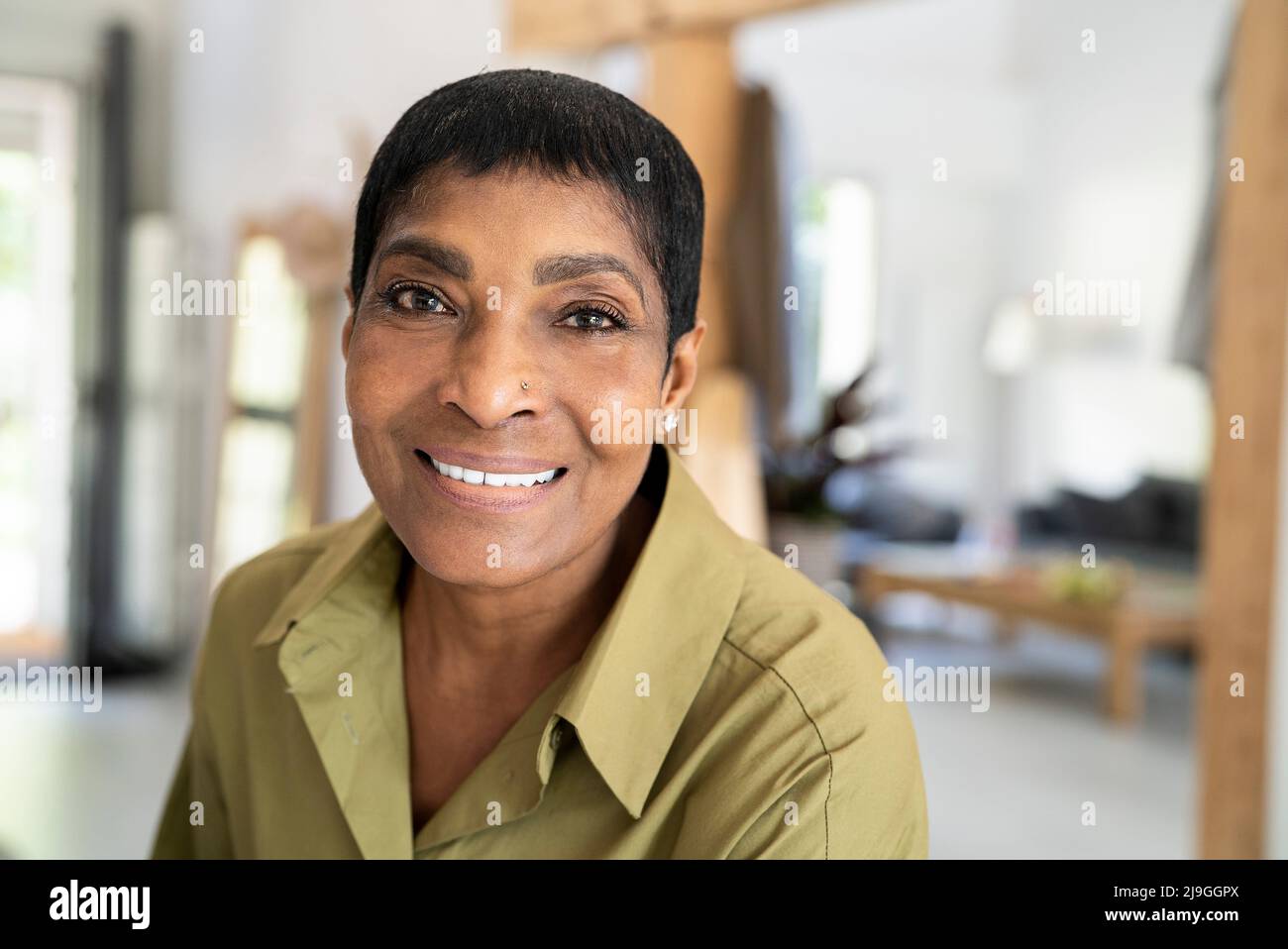 Gros plan d'une femme mûre souriante assise à la maison Banque D'Images
