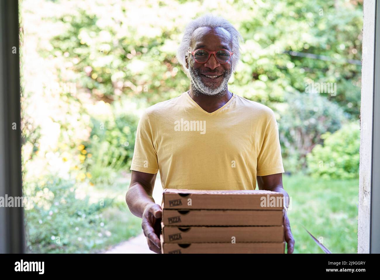 Portrait d'un livreur senior livrant une pizza Banque D'Images