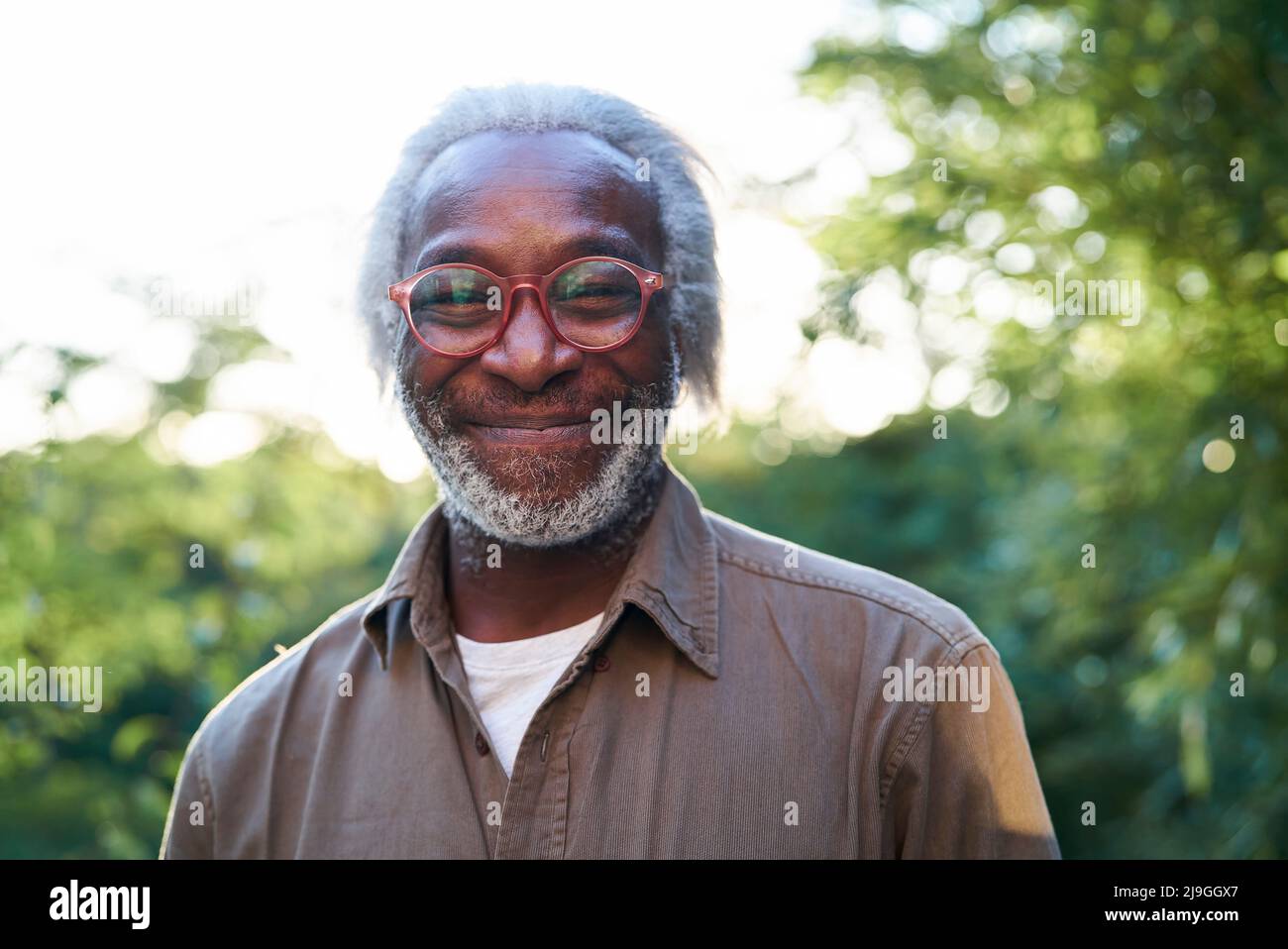 Gros plan d'un homme âgé souriant debout dans le jardin Banque D'Images