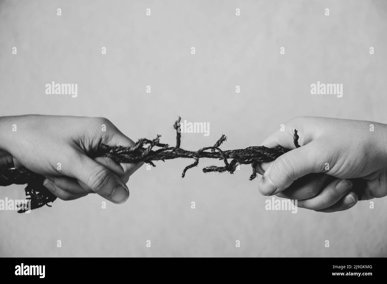 deux mains tirer la vieille corde sur un arrière-plan isolé, la force et la puissance Banque D'Images