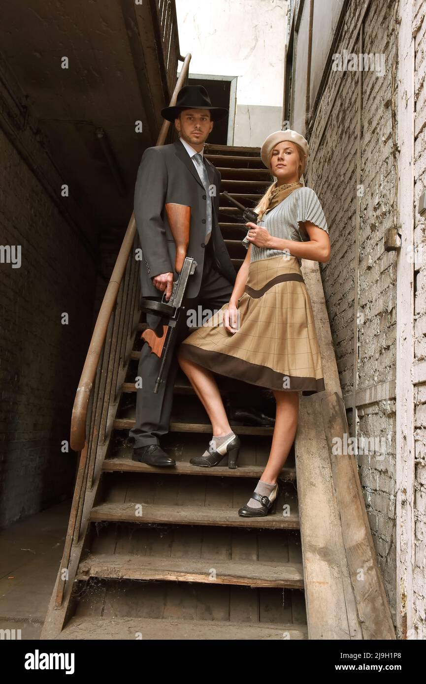 Un jeune couple s'habille avec des vêtements de style 1930. Ils portent chacun une arme comme ils agissent le rôle du célèbre duo de gangsters Bonnie et Clyde. Banque D'Images