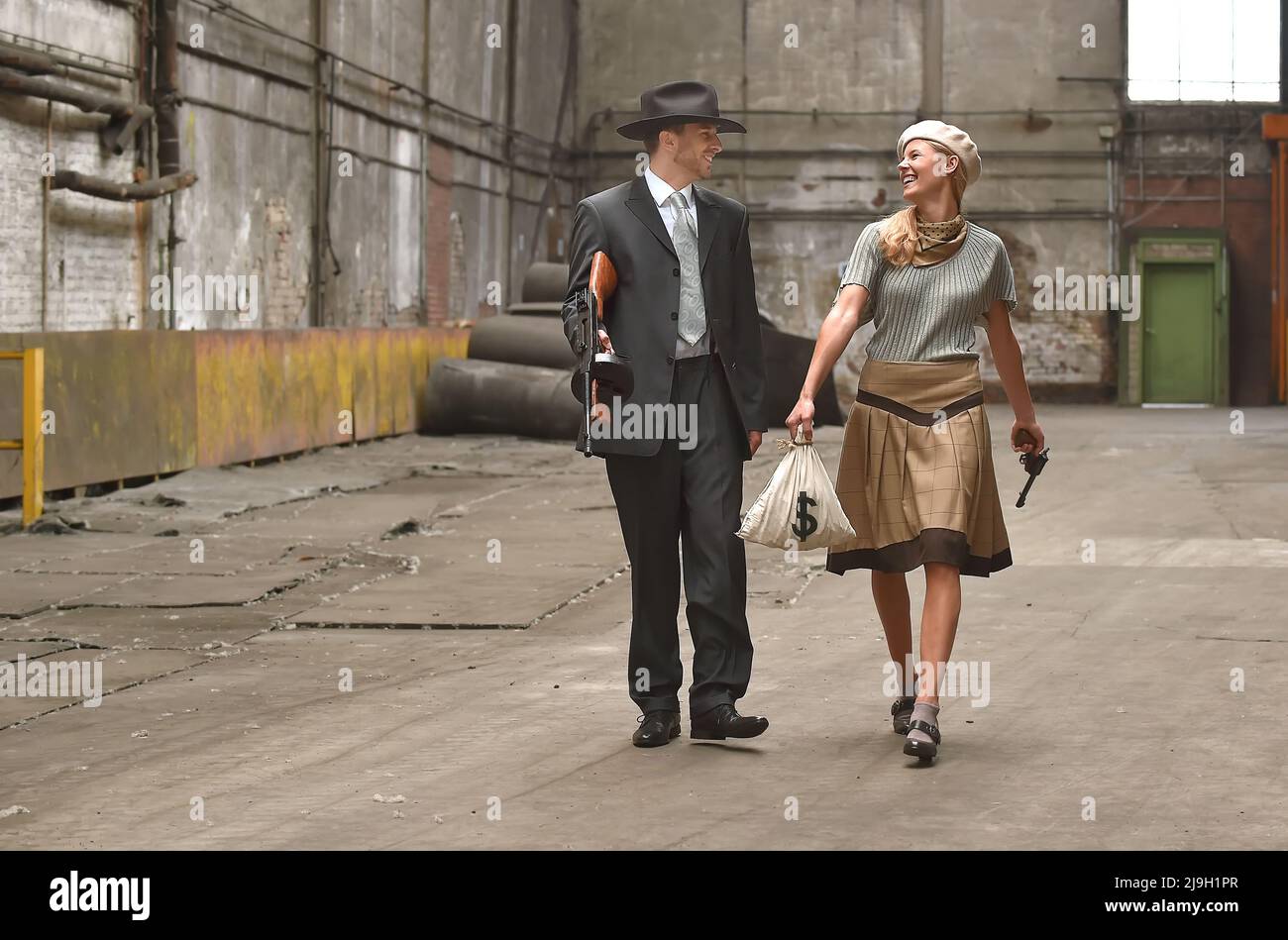 Un jeune couple s'habille avec des vêtements de style 1930. Ils portent chacun une arme comme ils agissent le rôle du célèbre duo de gangsters Bonnie et Clyde. Banque D'Images