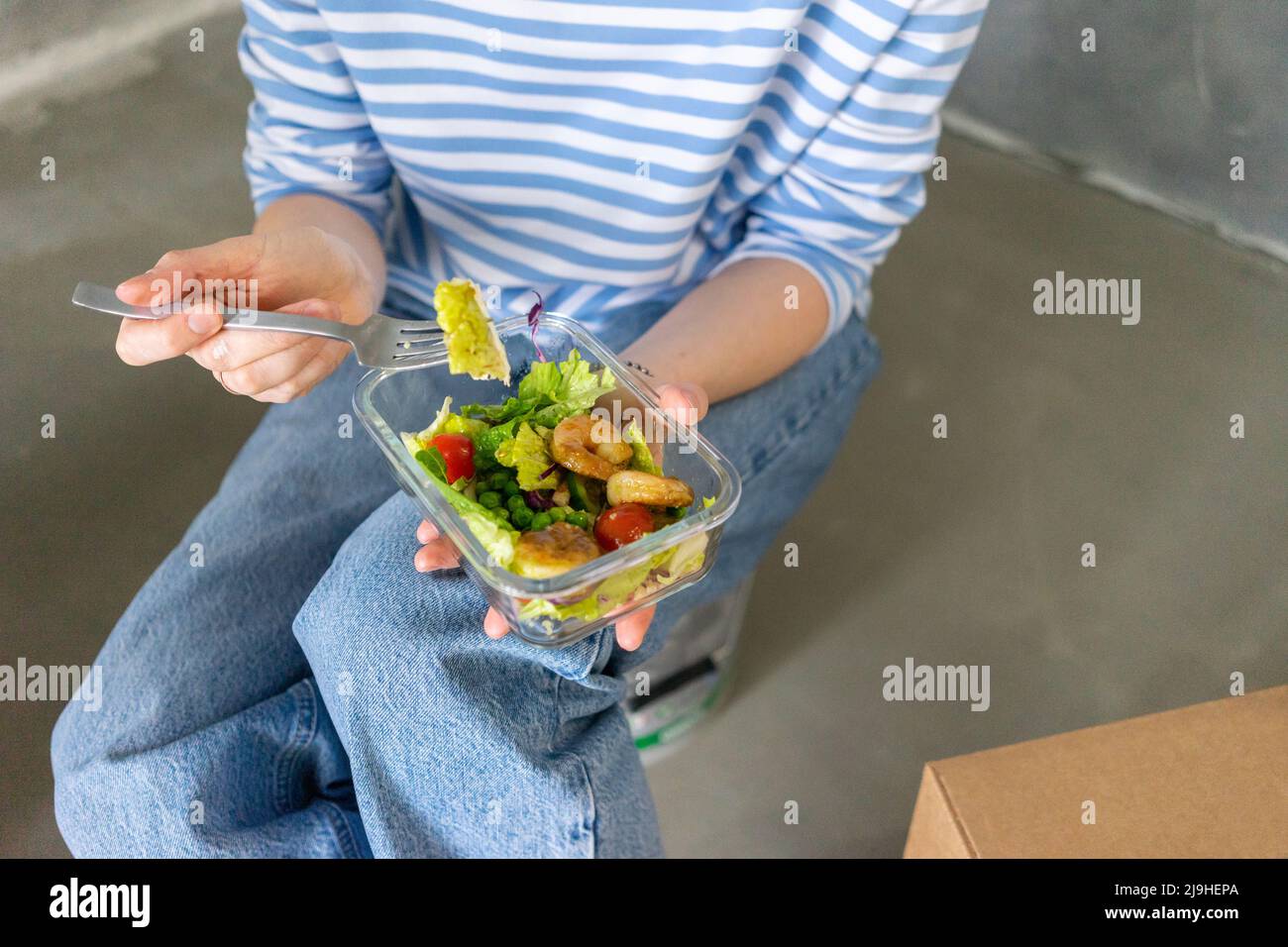 Mains de la femme tenant la fourchette et le contenant avec la salade de crevettes fraîches Banque D'Images
