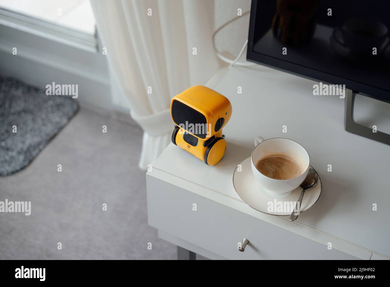 Ai robot jouet par tasse de café sur table à la maison Banque D'Images