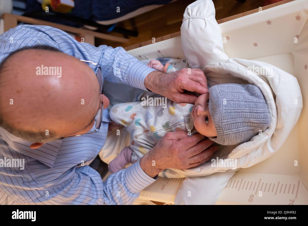 Grand-père met une veste chaude pour un bébé garçon. Papa habille un enfant  en vêtements d'hiver sur le lit Photo Stock - Alamy