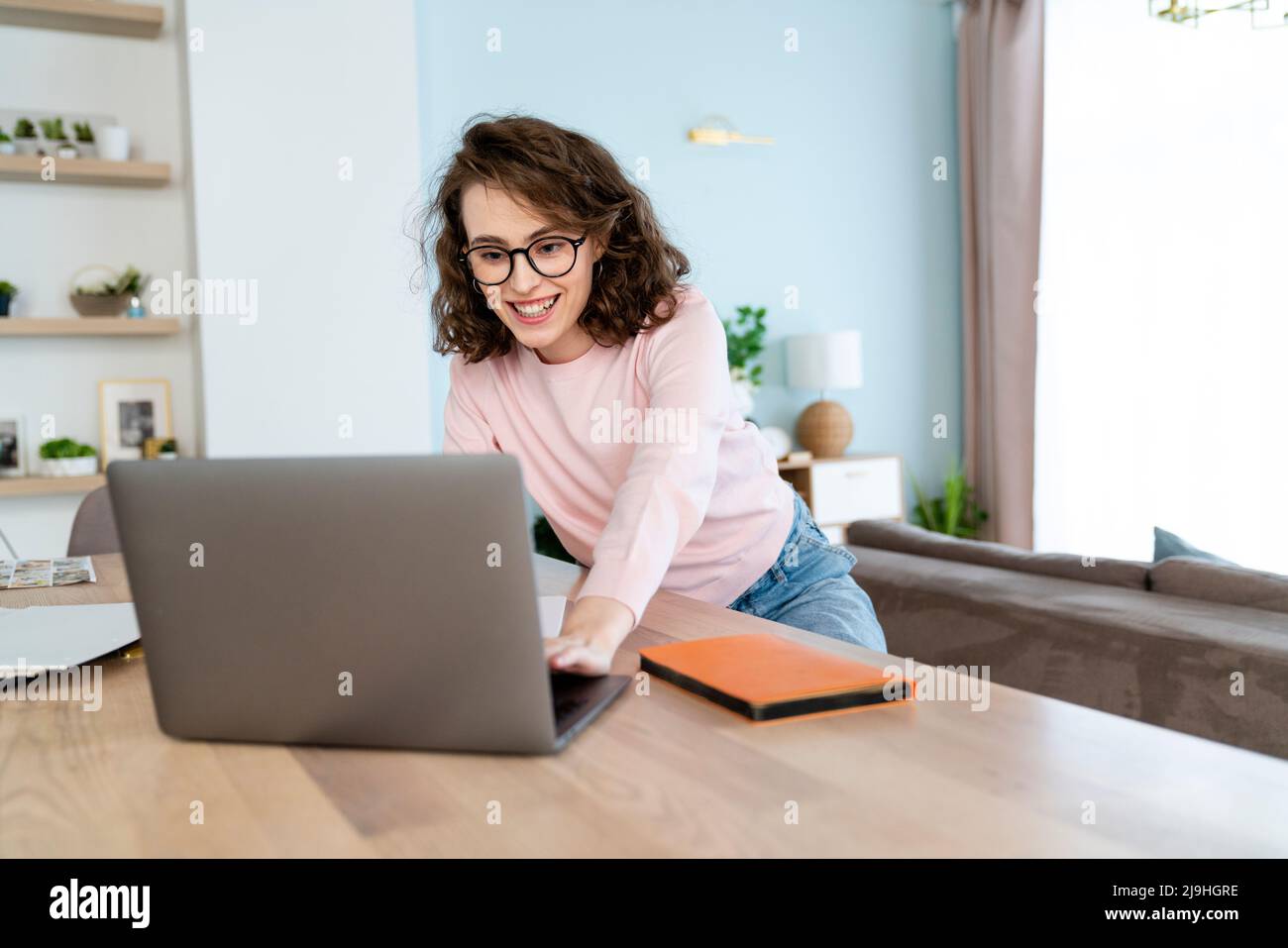 Un étudiant heureux étudiant qui étudie à la table dans le salon avec un ordinateur portable Banque D'Images