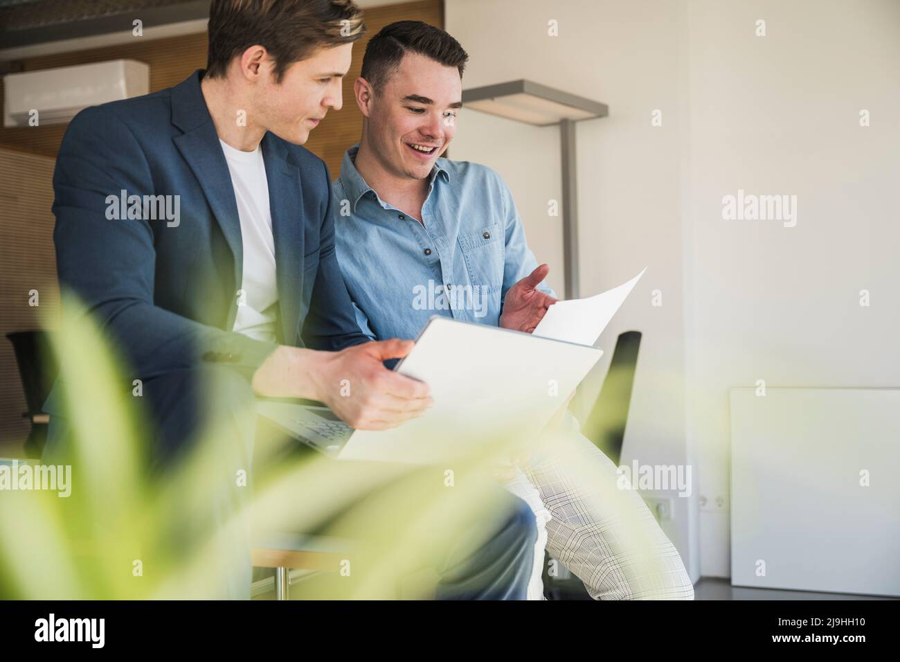 Deux collègues heureux avec ordinateur portable et documents au bureau Banque D'Images
