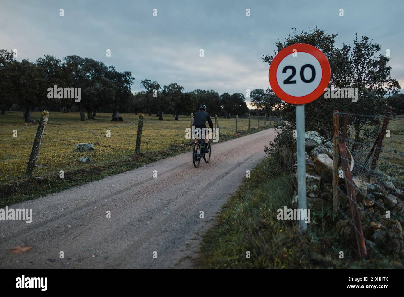 Cycliste roulant au lever du soleil en suivant le panneau de limitation de vitesse Banque D'Images