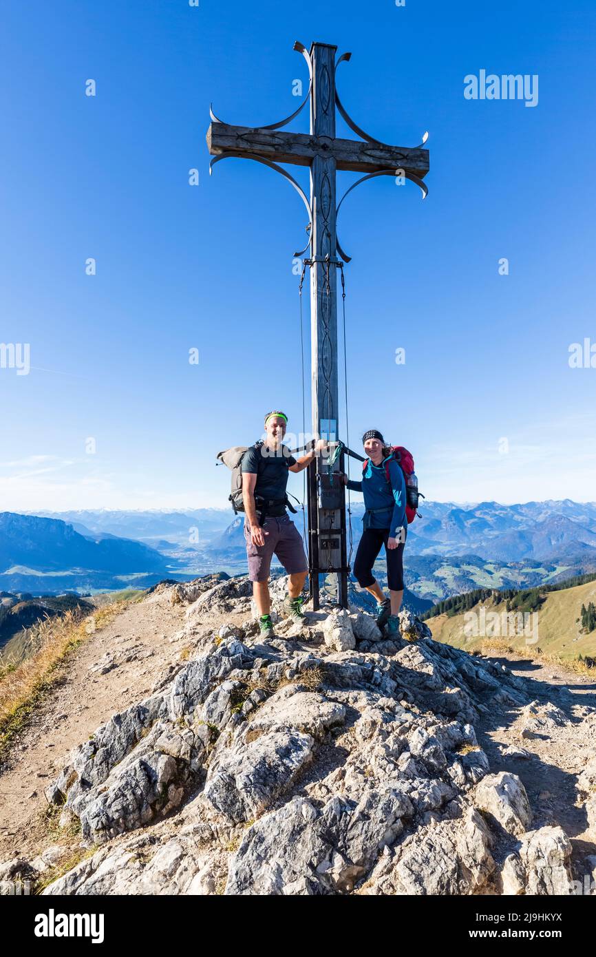 Allemagne, Bavière, deux randonneurs se posant devant le sommet de la croix sur la montagne Geigelstein Banque D'Images