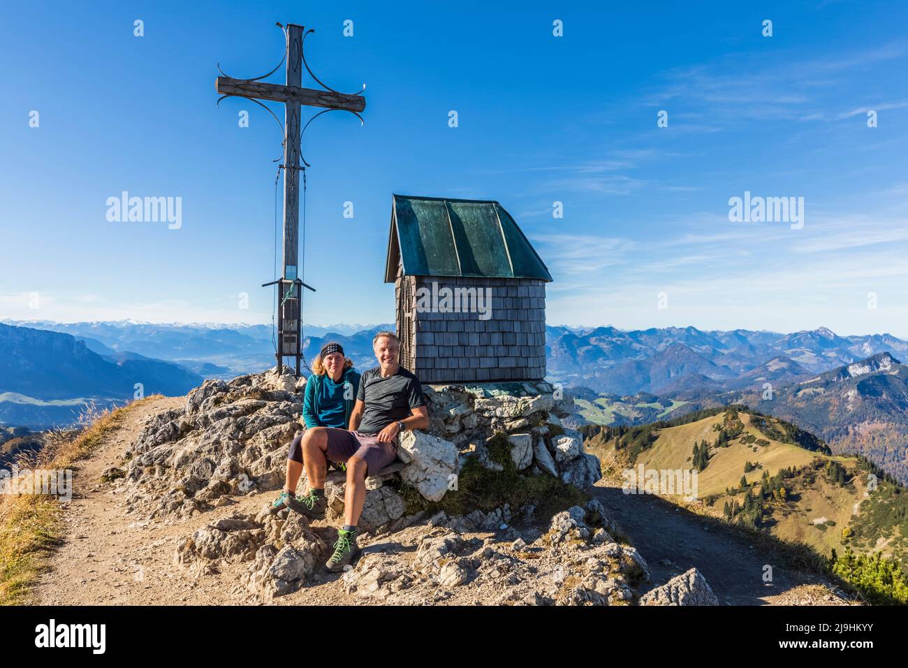 Allemagne, Bavière, deux randonneurs se détendant en face du sommet de croix sur la montagne Geigelstein Banque D'Images