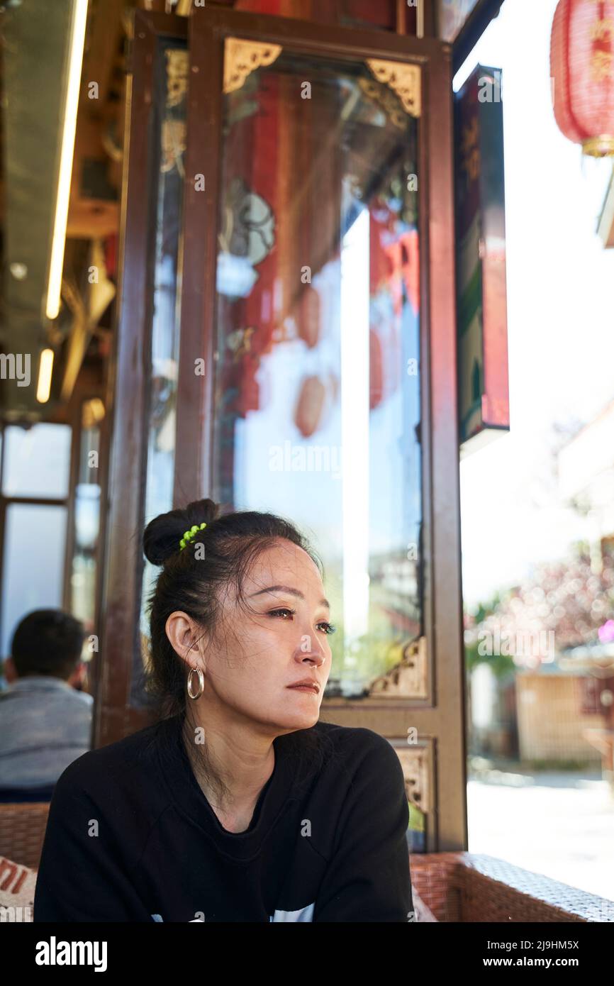 femme asiatique assise tristement dans un café avec des yeux teary Banque D'Images