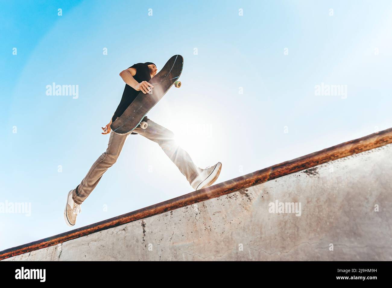 Homme avec planche à roulettes en train de courir au parc de skateboard par beau temps Banque D'Images