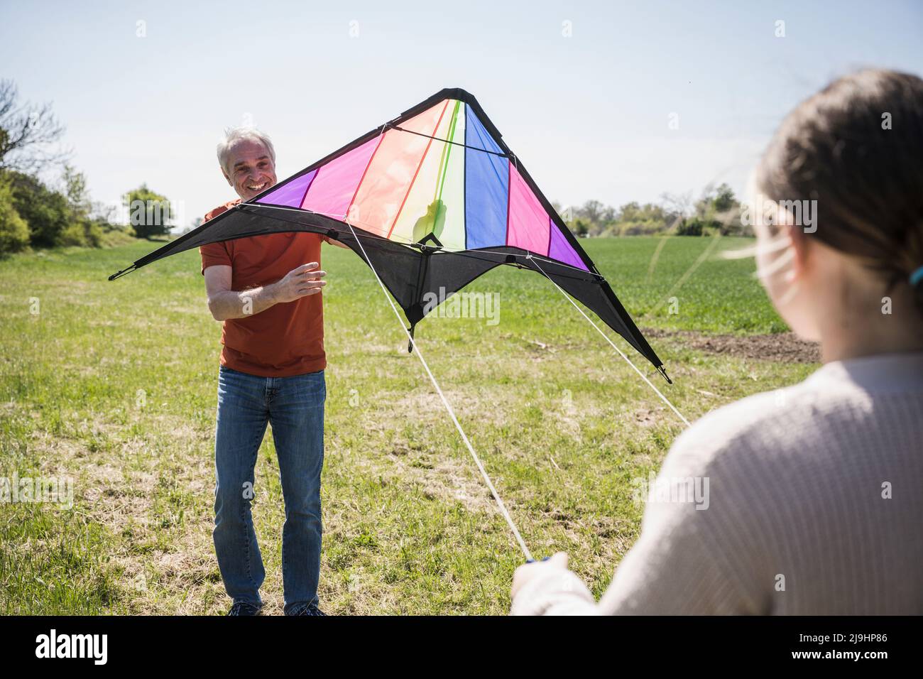 Grand-père souriant enseignant petite-fille volant cerf-volant le jour ensoleillé Banque D'Images