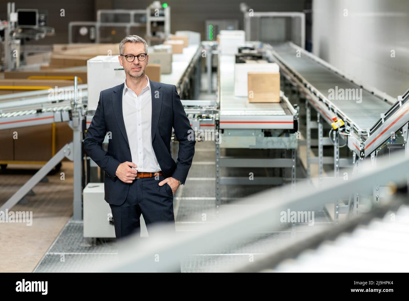 Homme d'affaires mature avec main dans la poche à l'entrepôt Banque D'Images