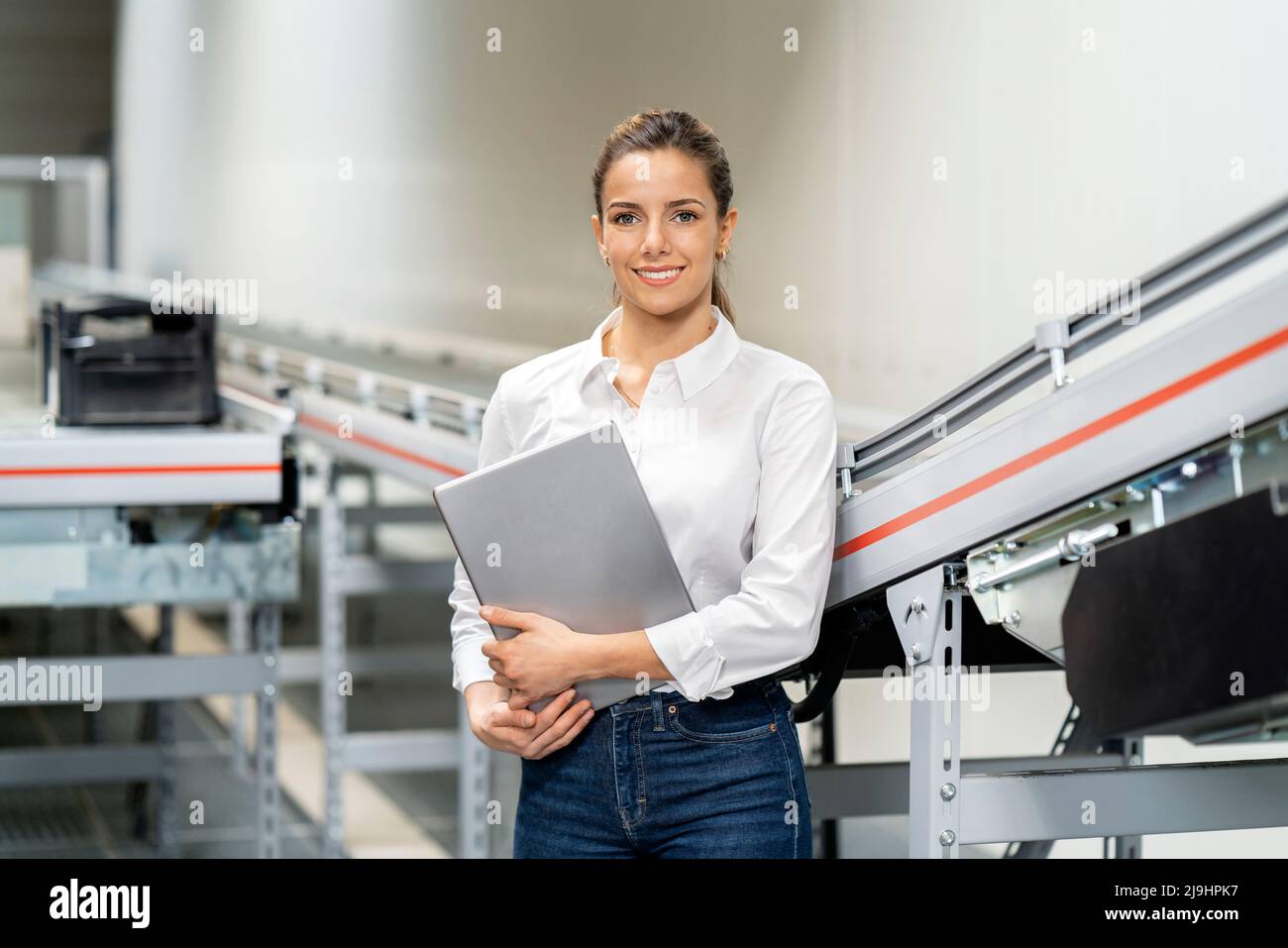 Femme d'affaires souriante avec une tablette à l'usine Banque D'Images