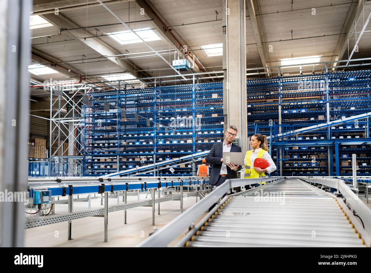 Responsable discutant sur ordinateur portable avec un employé de bureau dans l'entrepôt Banque D'Images