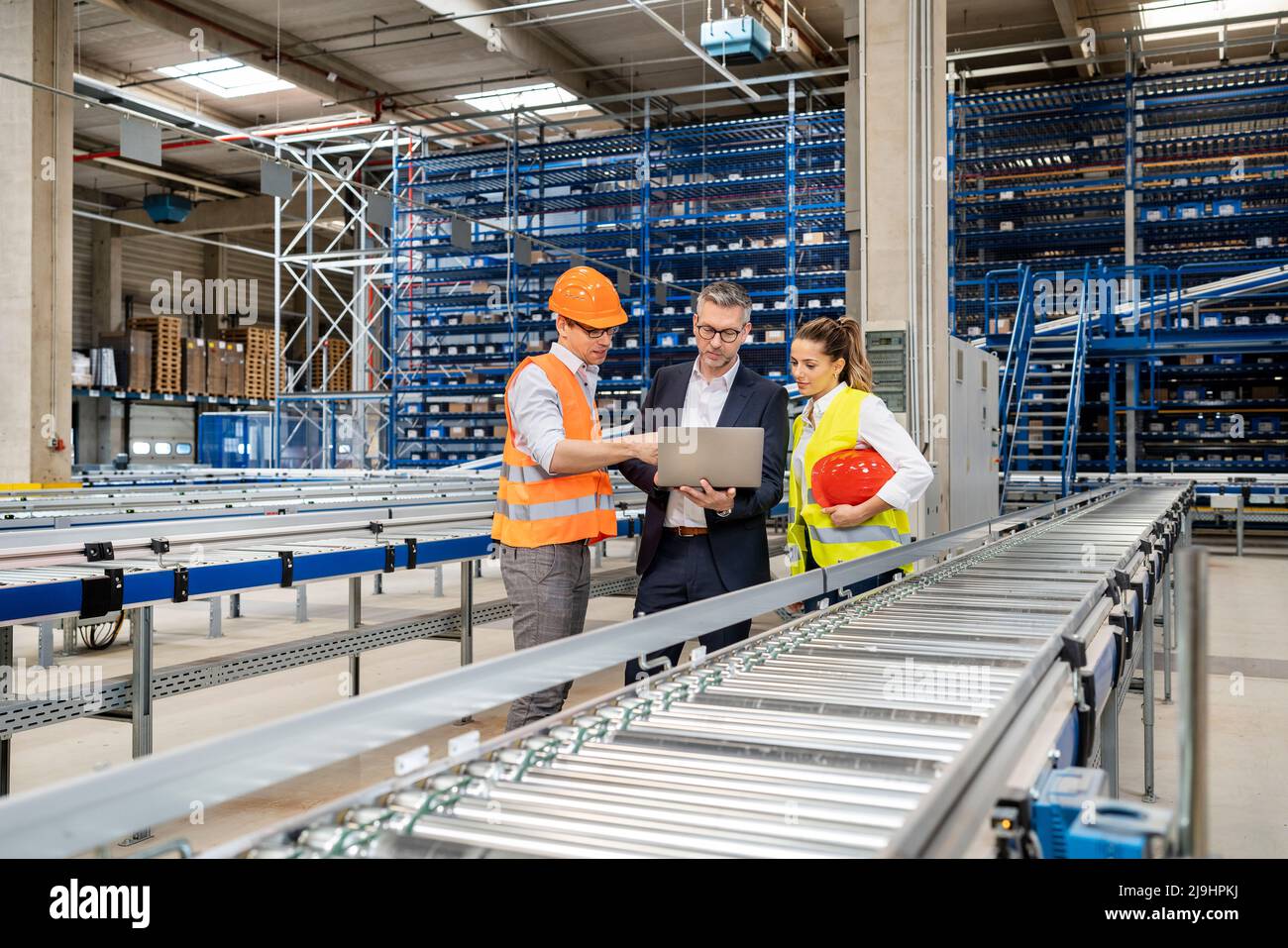 Les employés de bureau discutent avec le responsable de l'entrepôt au moyen d'un ordinateur portable Banque D'Images