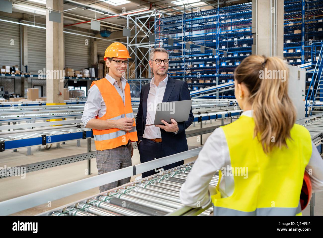 Homme d'affaires mature discutant avec des ouvriers en usine Banque D'Images