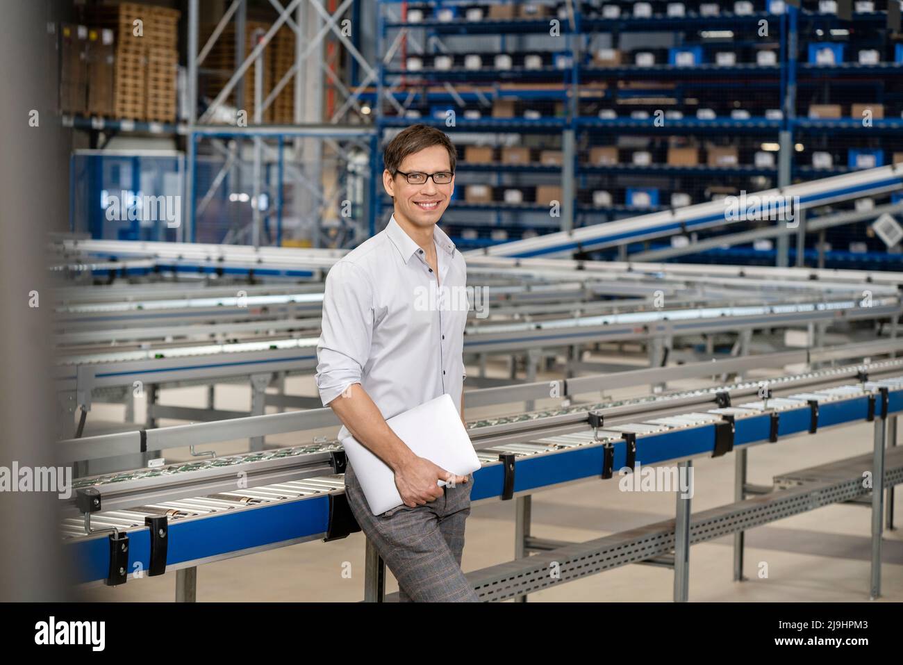 Homme d'affaires souriant avec ordinateur portable en usine Banque D'Images