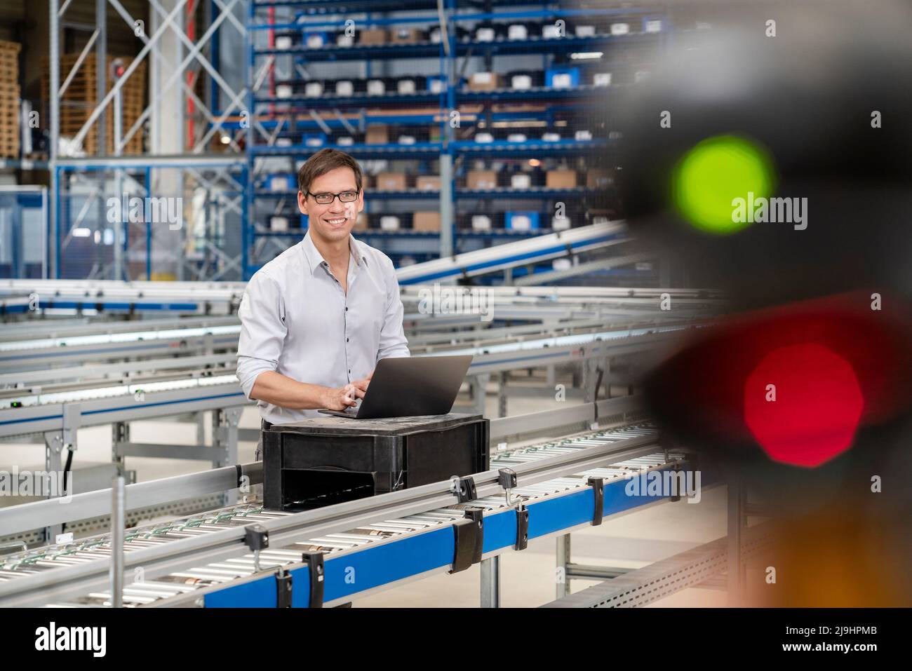 Homme d'affaires souriant et mûr avec un ordinateur portable à l'entrepôt Banque D'Images