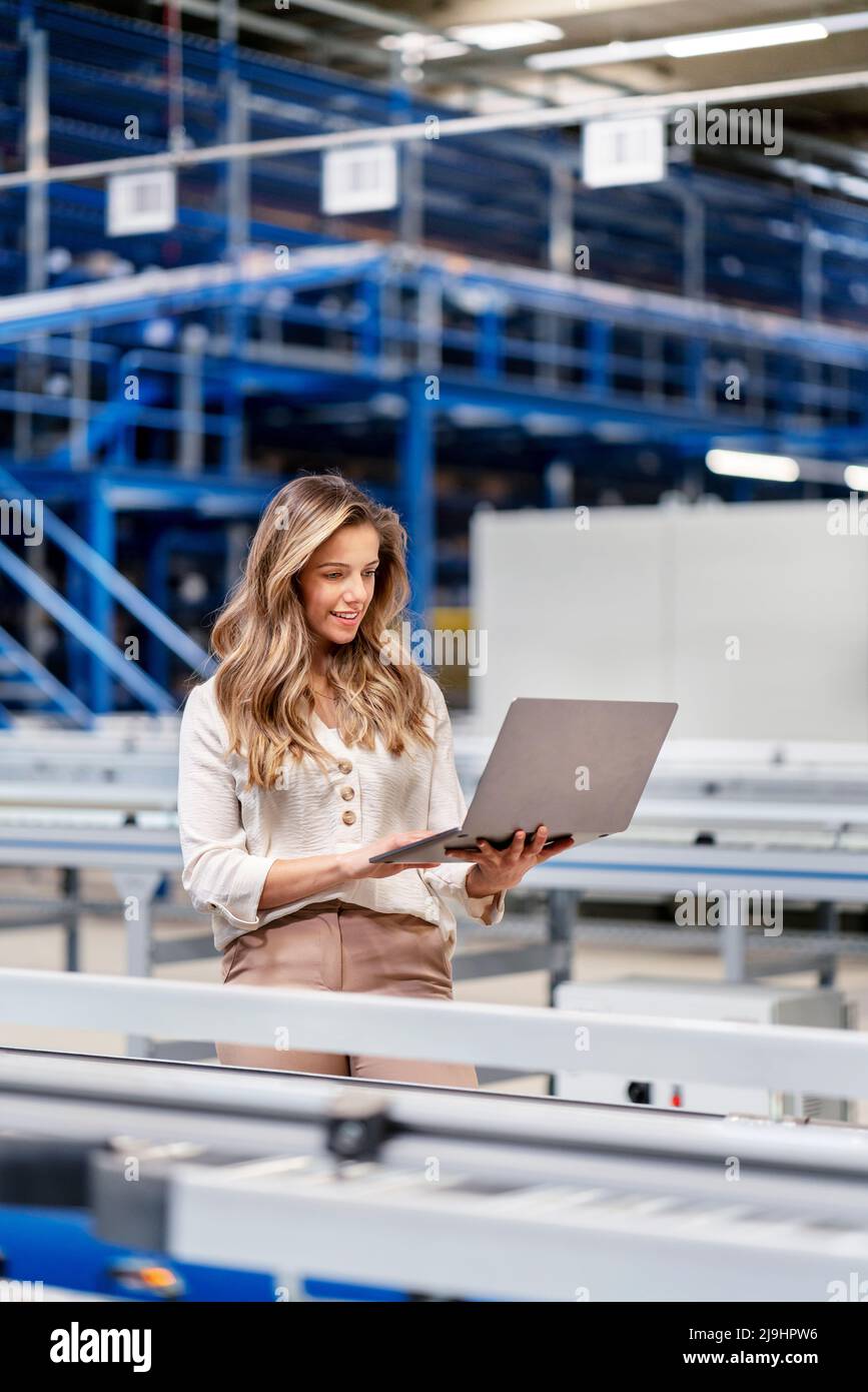 Jeune femme d'affaires utilisant un ordinateur portable travaillant en usine Banque D'Images