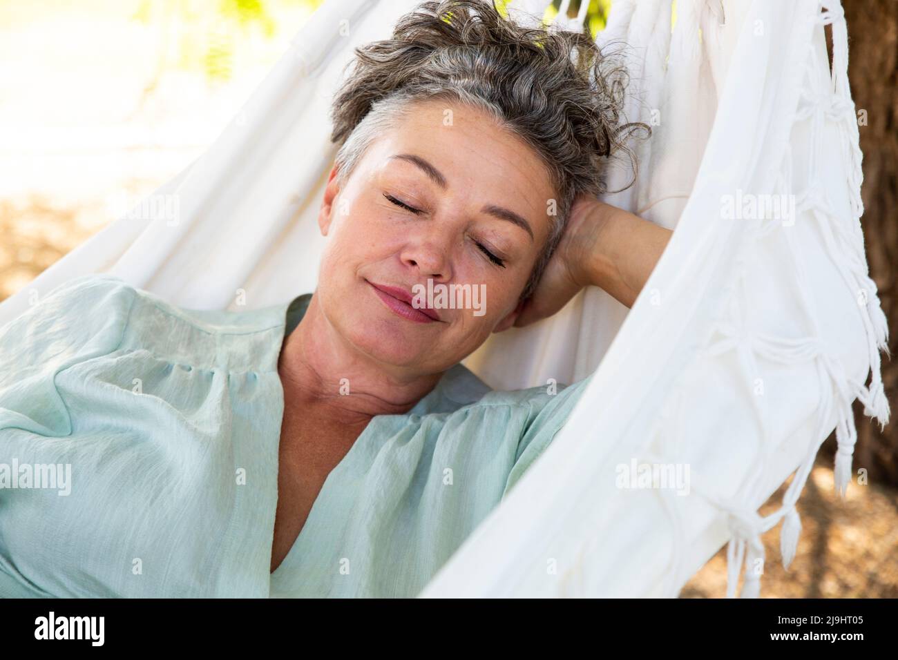Femme avec la main derrière la tête dormant dans un hamac Banque D'Images