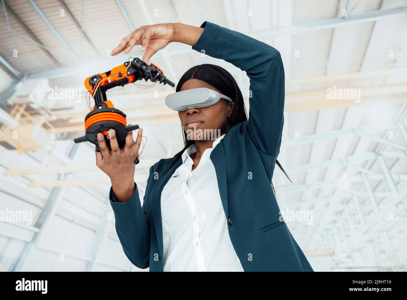 Ingénieur portant un simulateur de réalité virtuelle tenant le modèle de bras robotique en usine Banque D'Images