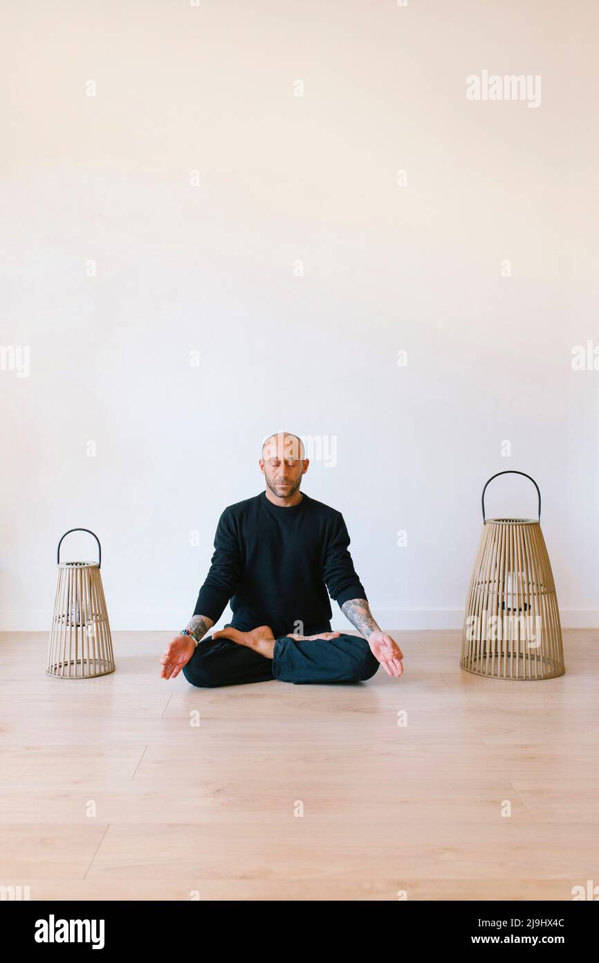 Homme assis en position lotus méditant au studio de yoga Banque D'Images