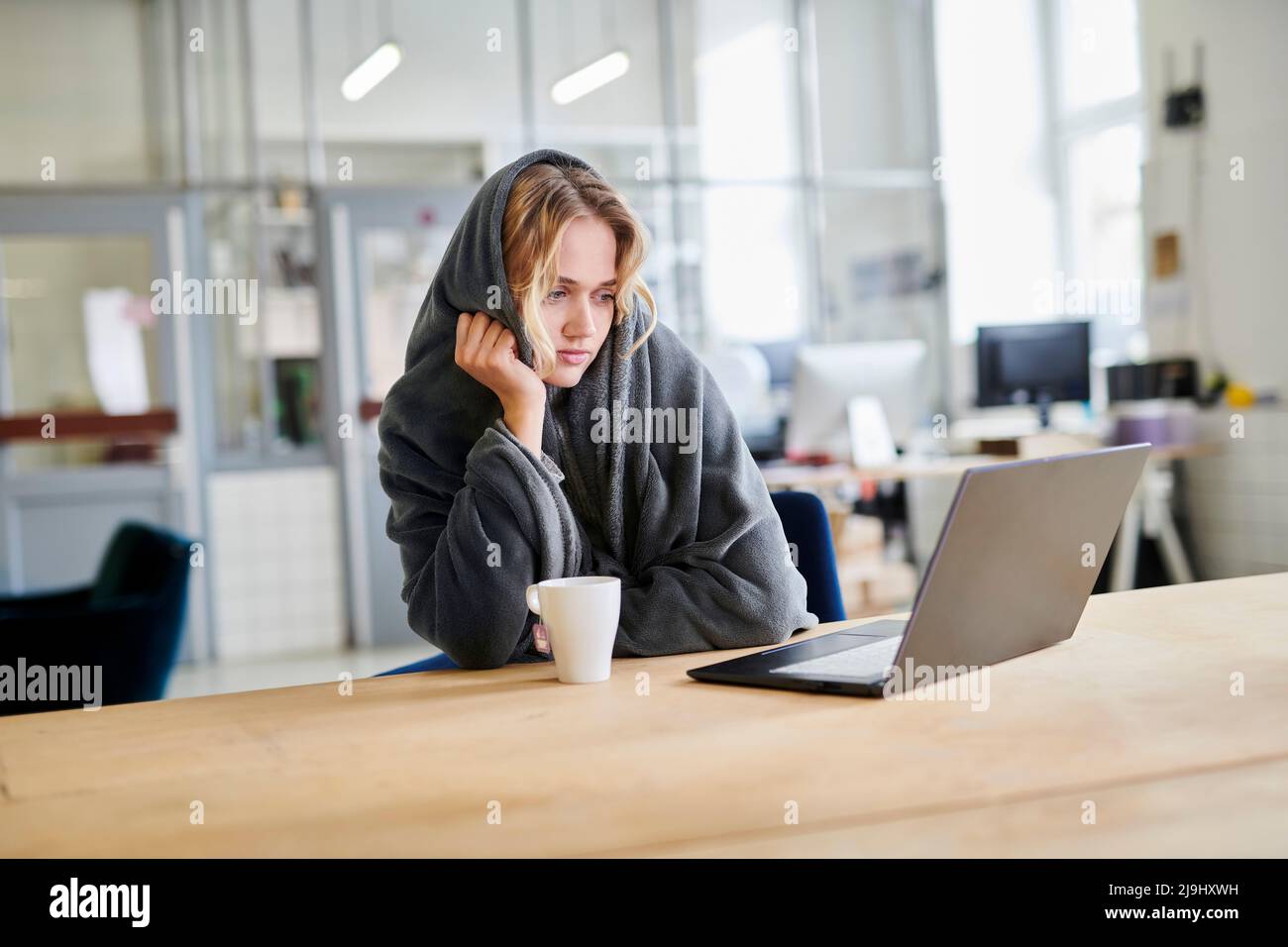 Jeune femme en confortable chaise longue assise au bureau avec ordinateur portable Banque D'Images