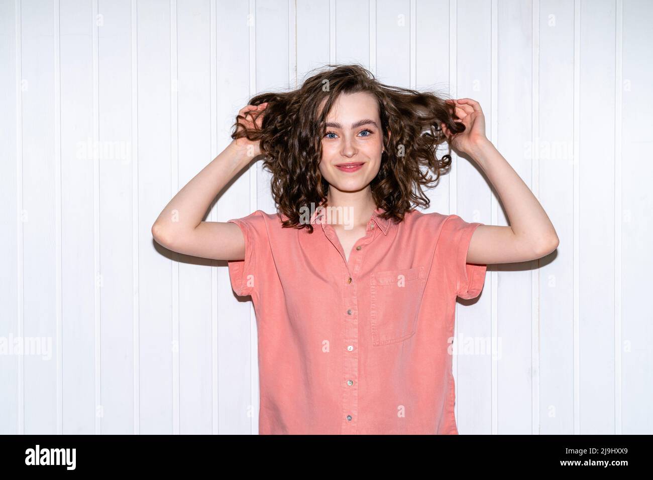 Souriante belle femme debout avec les mains dans les cheveux Banque D'Images