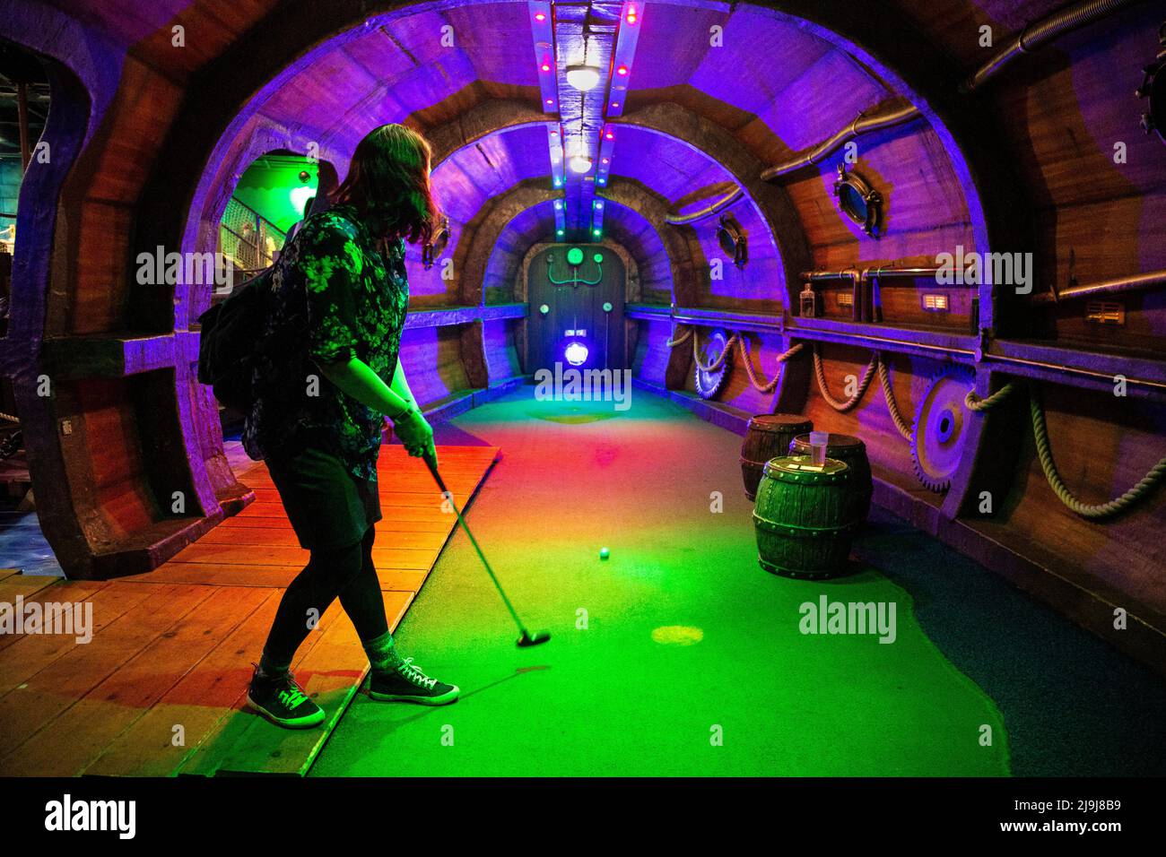 Femme jouant sur la piste de mini-golf Ocean Adventurer à MR Mulligan's Lost World, Stevenage, Hertfordshire, Royaume-Uni Banque D'Images