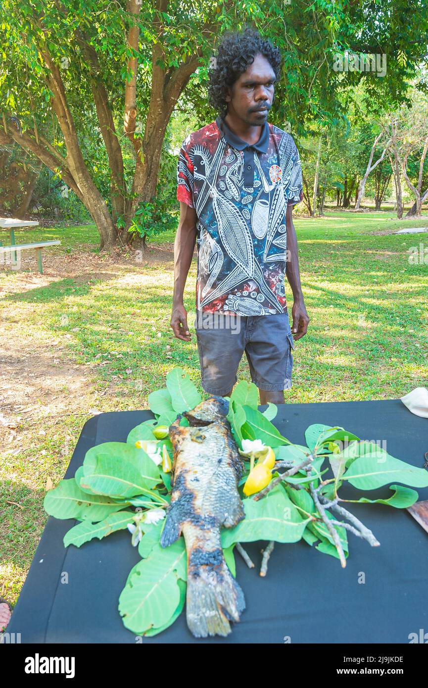 Jeune aborigène devant un poisson barramundi cuit sur des feuilles d'eucalyptus sur une table pendant le festival Taste of Kakadu, Cooinda, Kakadu Nationa Banque D'Images