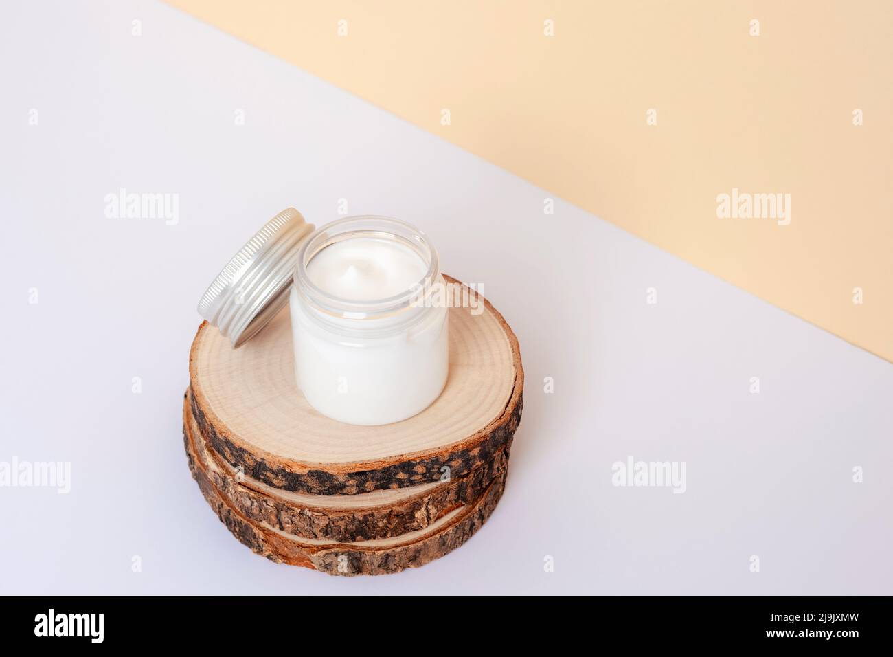 Pot crème sur support en bois sur fond blanc et beige. Concept de cosmétiques naturels. Gros plan. Banque D'Images