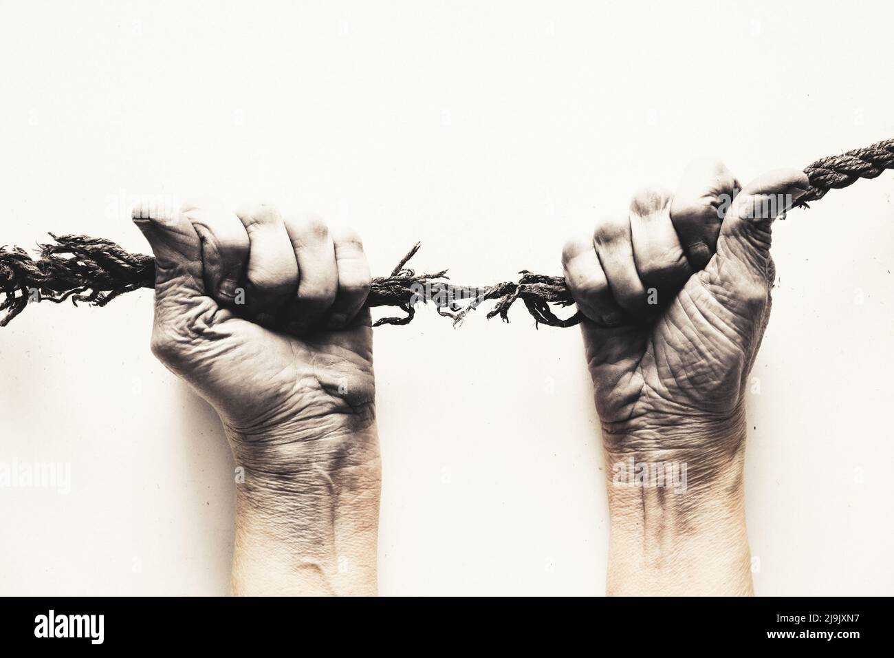 les mains tirent une vieille corde sur un fond blanc, force humaine Banque D'Images