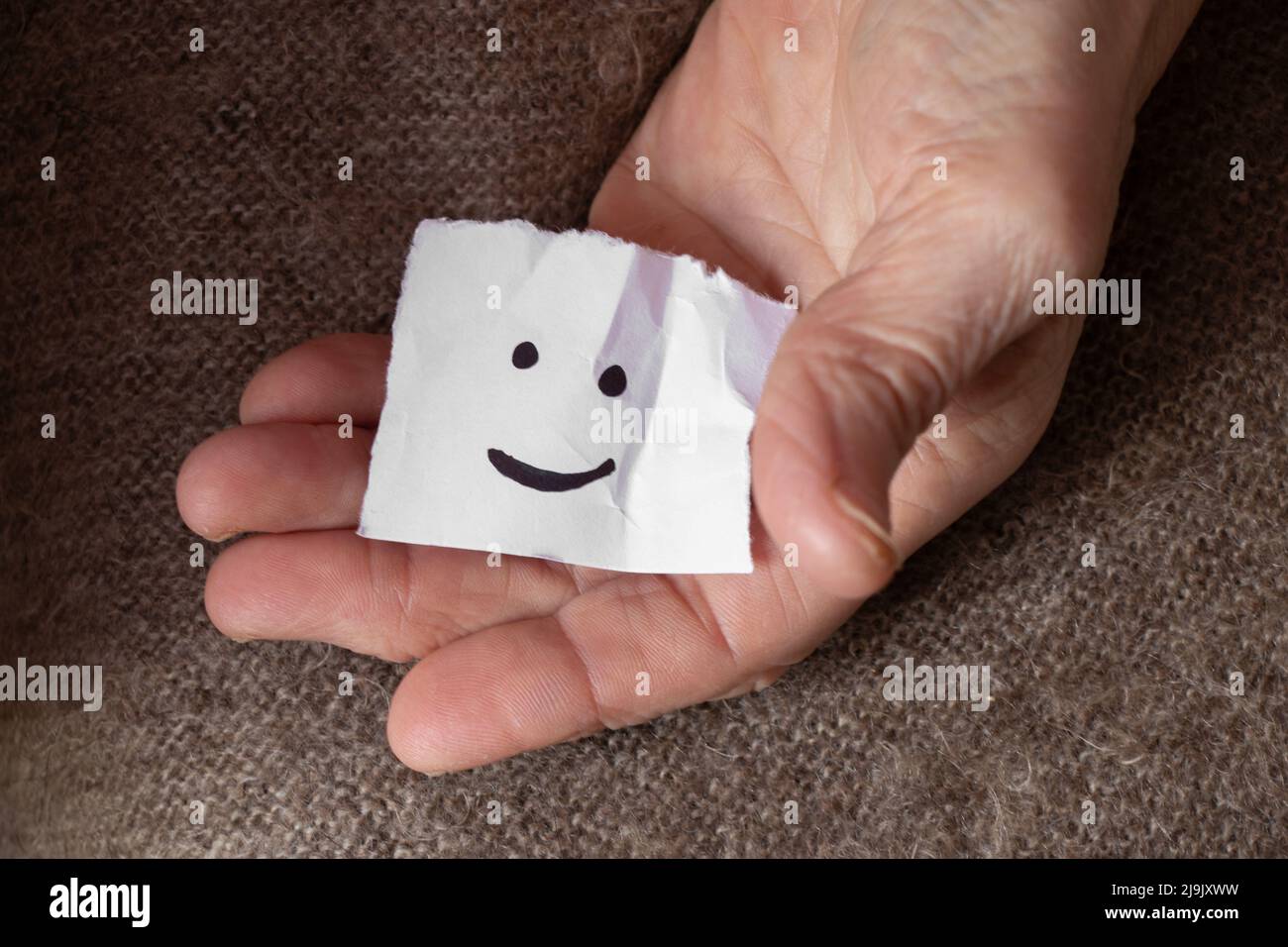 une émoticône gaie est dessinée sur un morceau de papier entre les mains d'une femme, une bonne humeur, de la joie et un sourire Banque D'Images