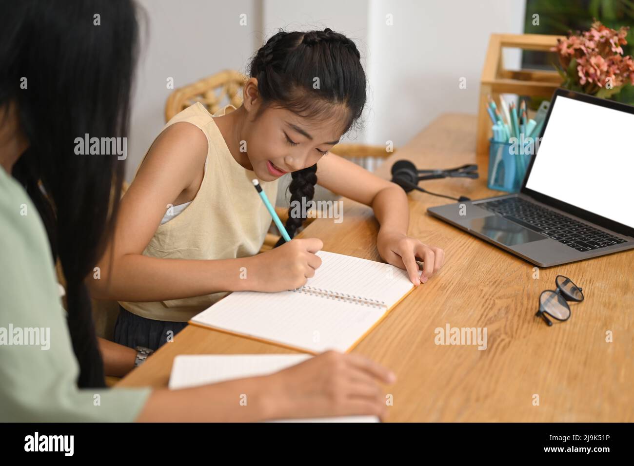 Bonne fille asiatique faisant des missions avec sa mère dans la cuisine à la maison Banque D'Images