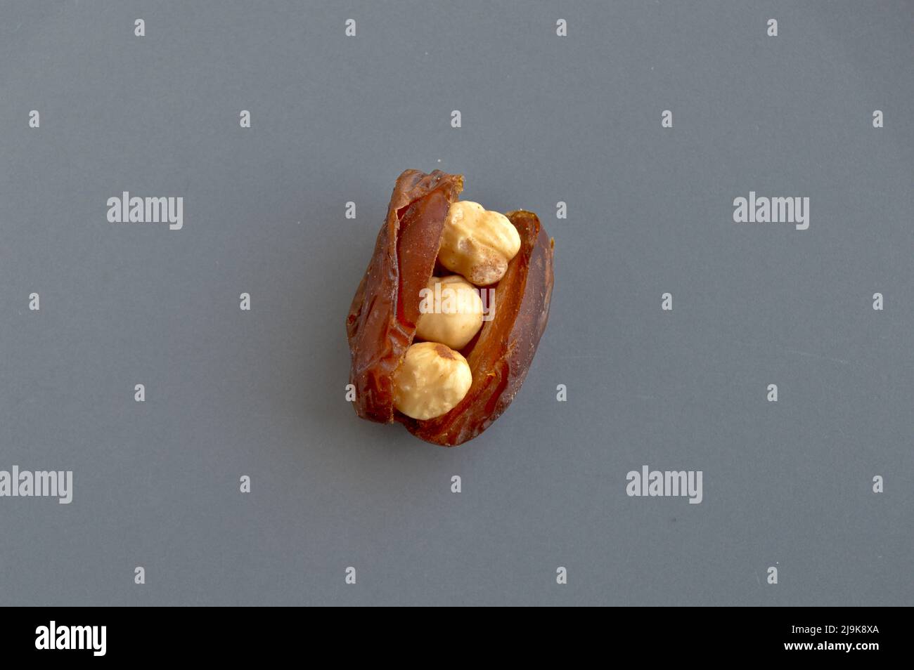 Biologique frais nutritif Hurma séché dattes medjool grains, noisettes placées à l'intérieur de la date, dans une assiette grise Banque D'Images