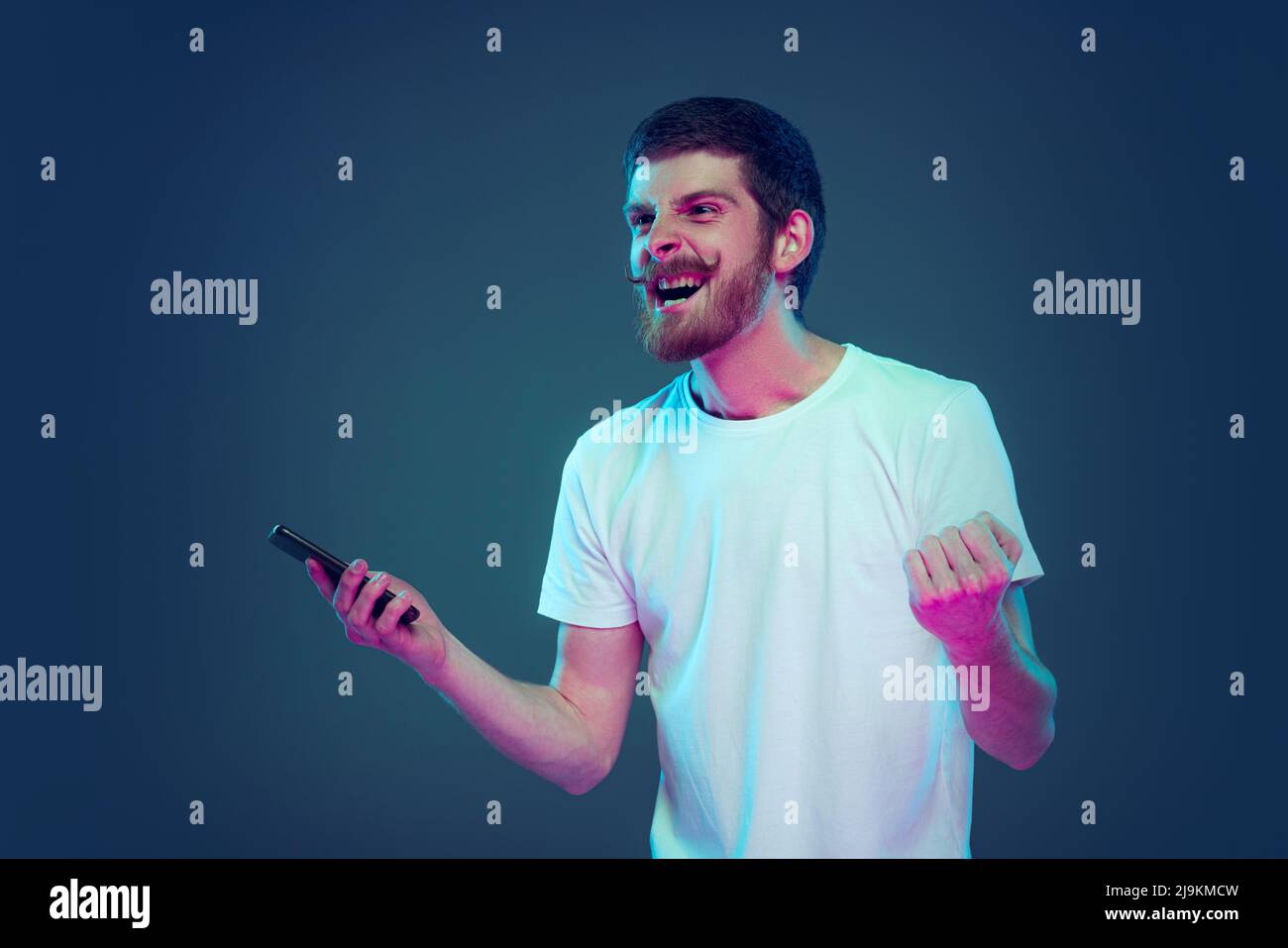 Portrait de l'homme excité, étonné criant isolé sur fond de studio bleu foncé, concept d'émotions humaines, expression faciale, ventes, publicité, mode Banque D'Images