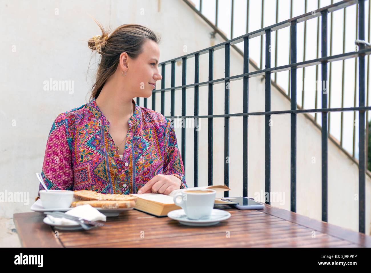 jeune femme ayant du pain grillé pour le petit-déjeuner sur la terrasse du bar Banque D'Images