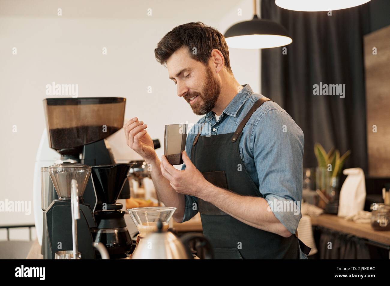 Le barista souriant apprécie l'arôme des grains de café à la cafétéria Banque D'Images