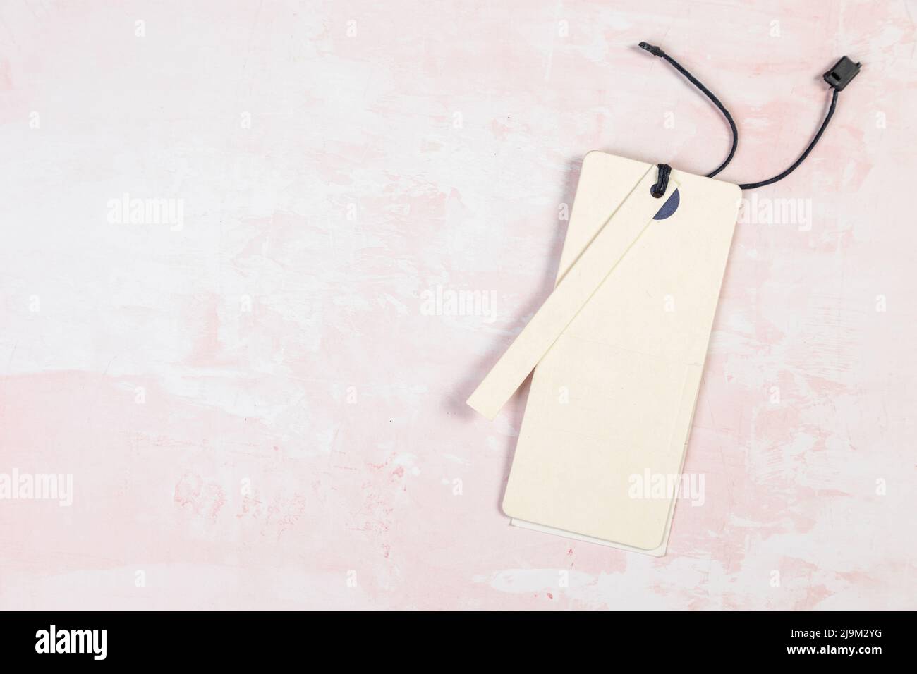 Étiquette de vêtement, modèle de maquette d'étiquette vierge sur une table rose Banque D'Images