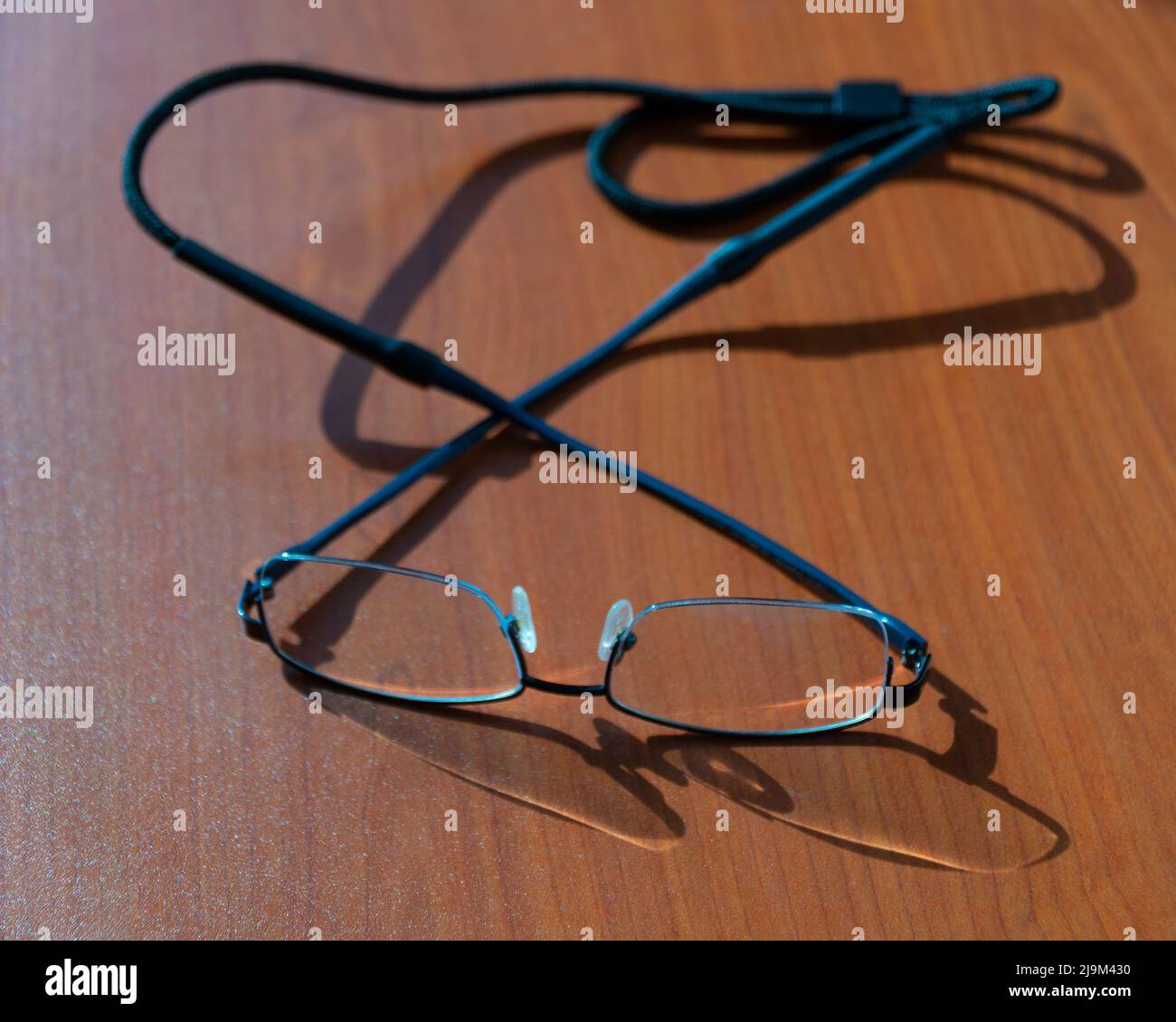 Lunettes avec lanière de cou sur une table en bois marron avec mise au point sélective. Banque D'Images