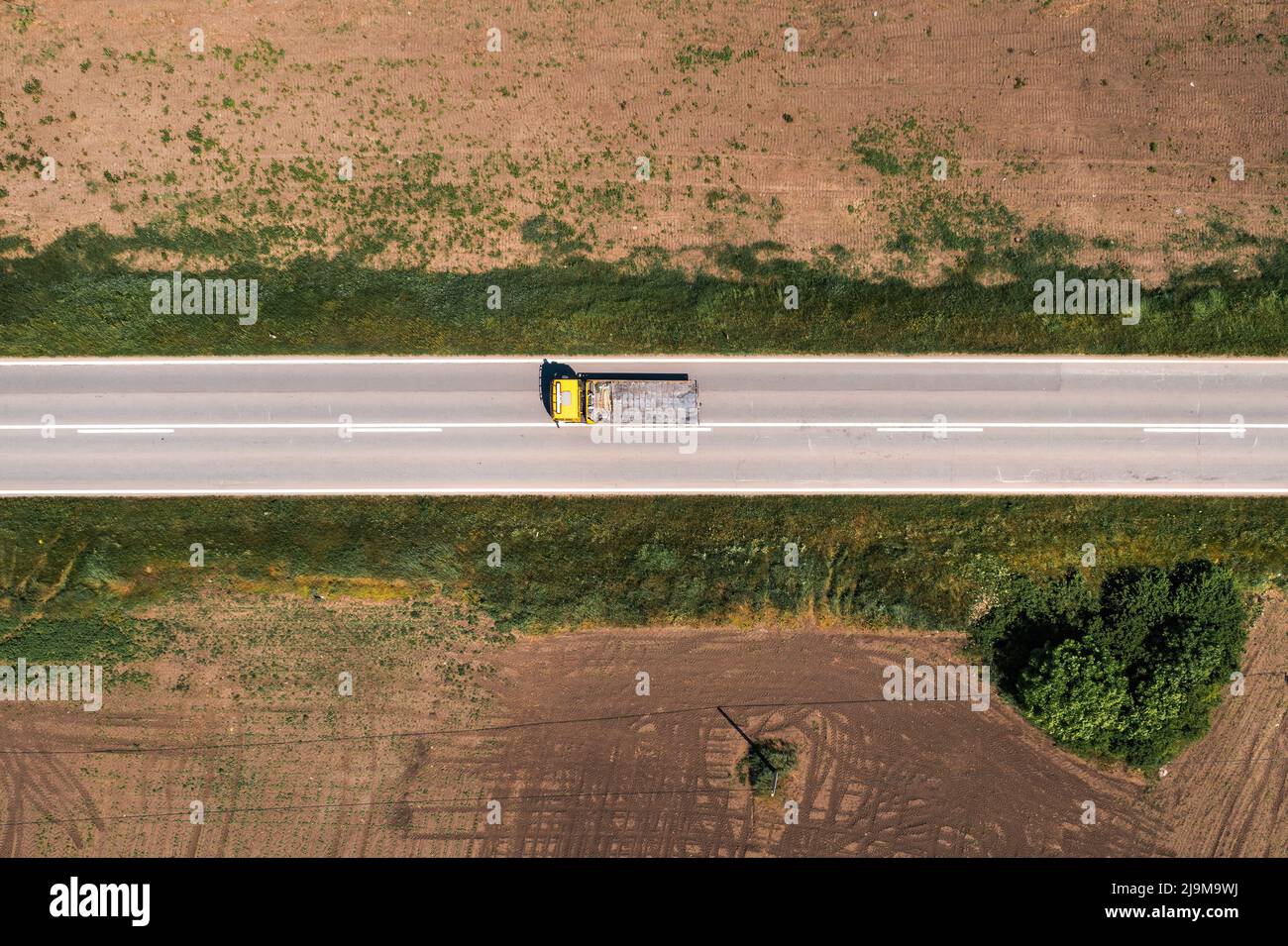 Camion-benne industriel avec remorque vide sur l'autoroute à travers le paysage de campagne, drone pov aérien tourné directement au-dessus le jour ensoleillé de printemps. Indus Banque D'Images
