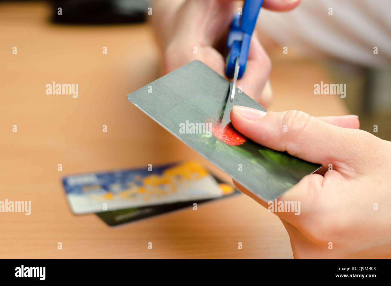 Gros plan des mains de femmes coupant une carte en plastique de banque avec des ciseaux Banque D'Images