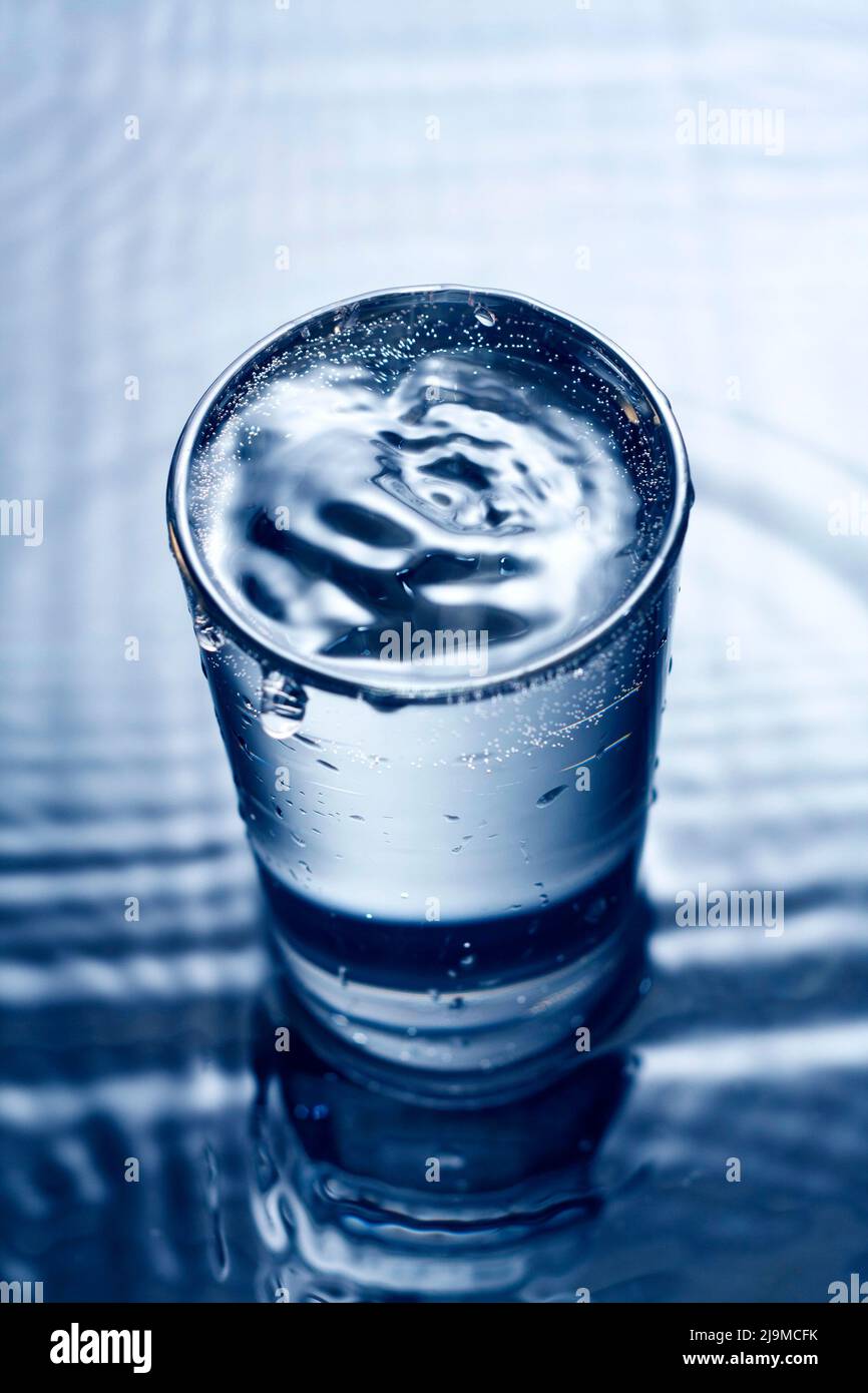 Image monochrome bleue des éclaboussures d'eau dans un verre. Banque D'Images