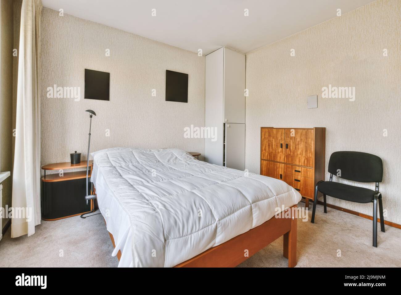 Commode en bois vintage près d'un lit confortable avec une couverture placée près du radiateur dans la chambre lumineuse à la maison Banque D'Images