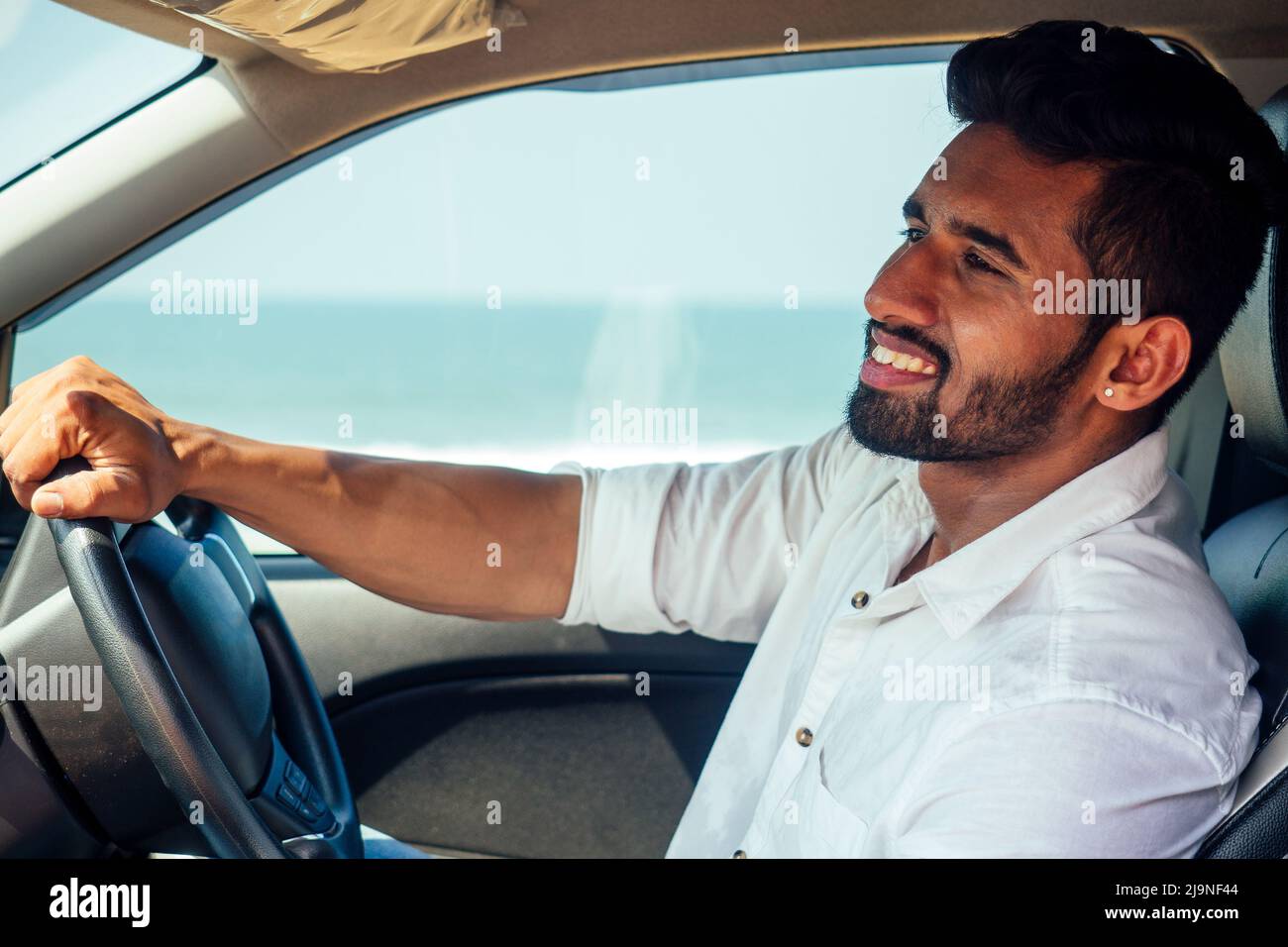 Voyage vacances heureux indien dans blanc chemise collier acheter nouvelle voiture et montrant la clé, assis en voiture sur la plage mer inde octan Goa. Un voyage à la Banque D'Images